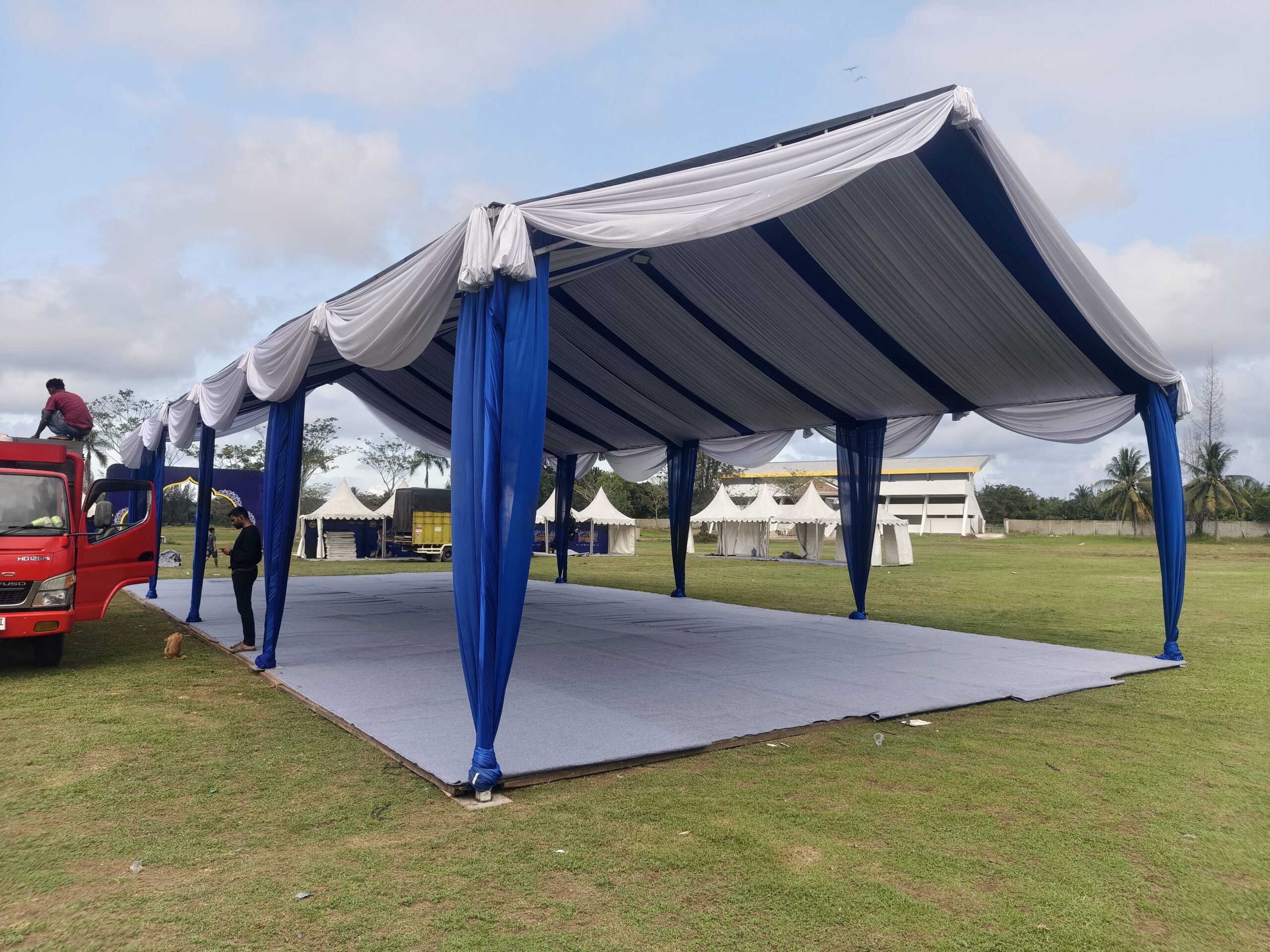 Pengaturan tenda formal dengan barisan kursi seminar dan podium rapi
